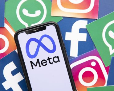A smartphone screen displaying the Meta logo, flanked by the logos of Facebook, Instagram, and WhatsApp, illustrating the reach of Meta AI across social platforms.